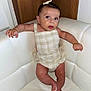 baby, infant, child, romper, white_chair, leather_chair, wooden_background, bow, cute, sitting, indoor, person, skin, face, eyes, hand, foot, expression, young, portrait