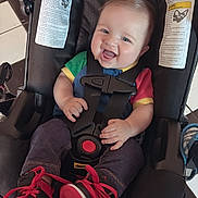 Xander joined the competition — help win amazing prizes! baby, car_seat, child, smiling, happy, infant, sneakers, colorful_clothing, straps, floor_tiles, red_shoes, cute, indoor, young_child, head, face, person, feet, jeans, laughter