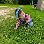 Lina a rejoint le concours — aidez-le/la à gagner de superbes lots ! bow, casual_clothing, child, clover, crawling, curious, daylight, denim_overalls, flowers, garden, grass, greenery, headband, long_sleeve_shirt, nature, outdoor, playing, sunny, toddler, young_child