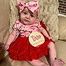 baby, infant, child, pink_bow, cherry_pattern, red_skirt, two_months_sign, couch, beige, plush_blanket, cute, portrait, indoors, person, smiling, fashion, headband, sitting, happy, skin