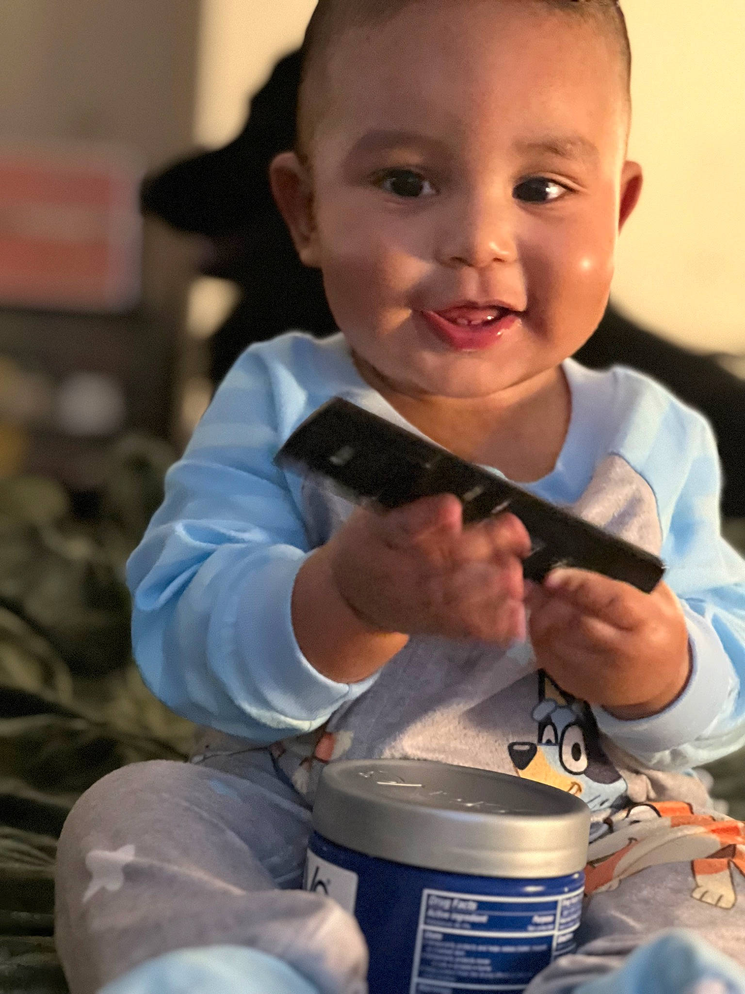 Kyle is registered to the contest to win money with this photo: baby, child, drinkware, finger, fun, gesture, hairstyle, happy, person, personal_protective_equipment, plastic_bottle, play, recreation, sitting, smile, t_shirt, thumb, toddler, vacation