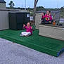 calm, casual, child, cross_legged, daytime, fun, grass, gravel, green_platform, meditation_pose, nature, outdoor, pink_clothing, play, relaxation, sitting, sky, storage_shed, tree, two_children