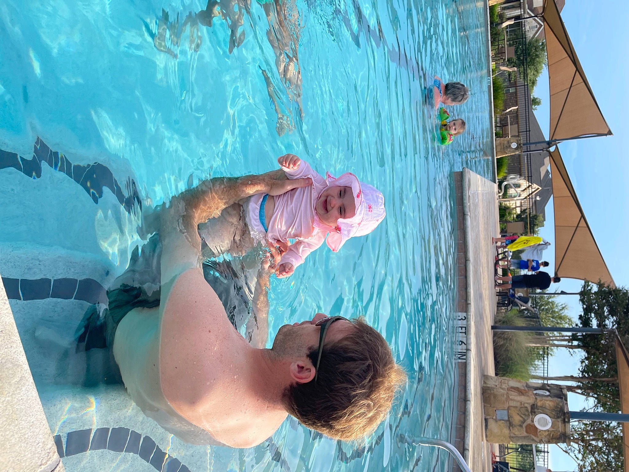 Emerson is registered to the contest to win money with this photo: azure, baseball_cap, bathing, child, elbow, fun, happy, hat, headwear, joy, lake, leisure, person, recreation, shorts, sky, sunglasses, swimmer, swimming_pool, t_shirt