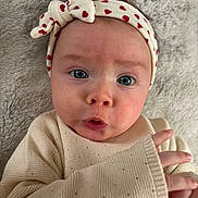 Esmée a rejoint le concours — aidez-le/la à gagner de superbes lots ! baby, infant, headband, heart_pattern, blue_eyes, knit_sweater, hand, face, expression, lying_down, soft_blanket, cute, closeup, child, portrait, skin, indoors, person, cozy, adorable