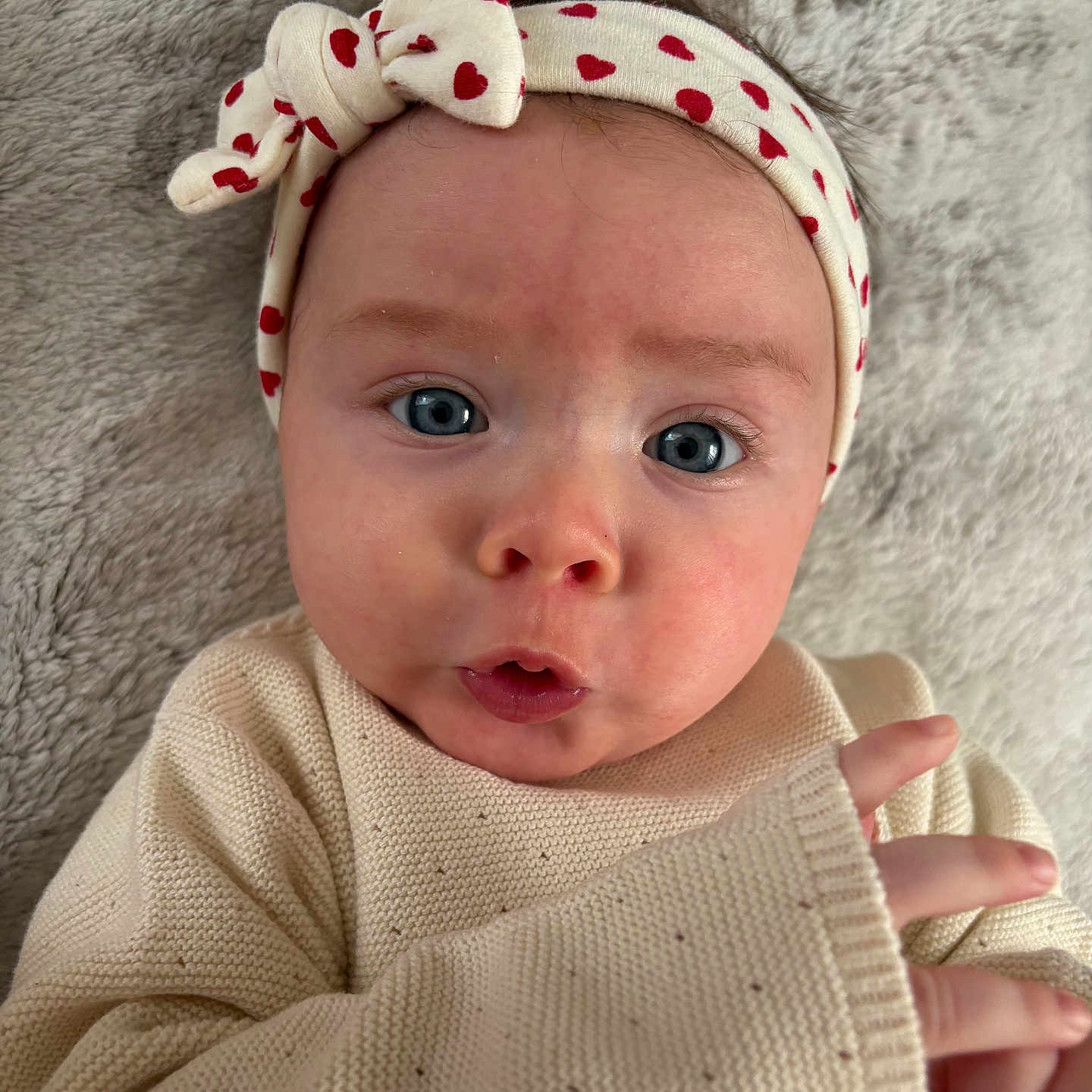 Esmée a rejoint le concours — aidez-le/la à gagner de superbes lots ! baby, infant, headband, heart_pattern, blue_eyes, knit_sweater, hand, face, expression, lying_down, soft_blanket, cute, closeup, child, portrait, skin, indoors, person, cozy, adorable