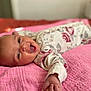 baby, infant, smiling, happy, lying_down, blanket, pink, floral_clothing, cute, portrait, indoors, soft_focus, child, skin, hand, face, expression, newborn, cozy, comfort