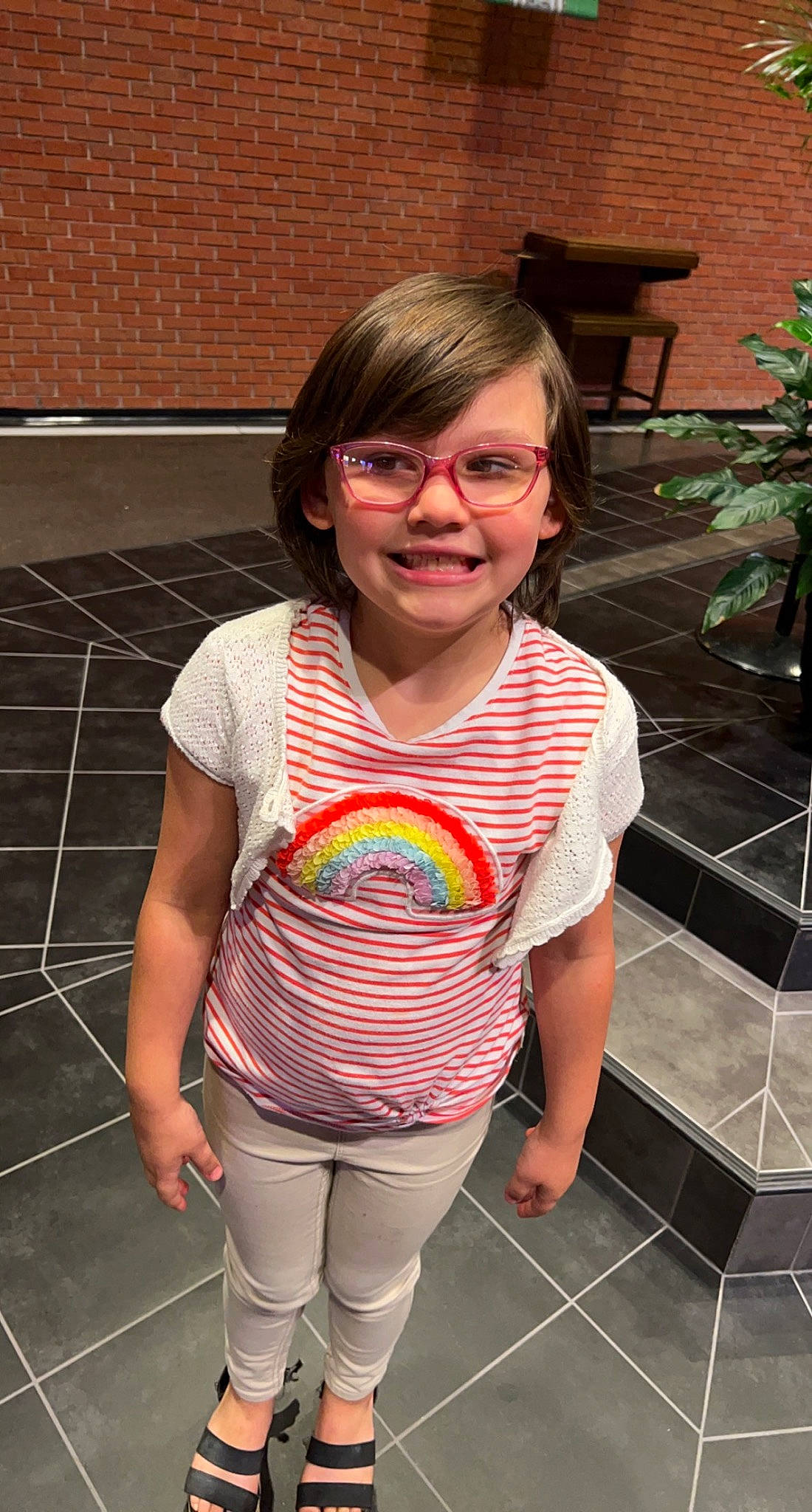 Aarabella is registered to the contest to win money with this photo: brick, eyewear, flooring, flowerpot, fun, glasses, happy, human_leg, joy, leg, leisure, pattern, person, pink, plant, smile, sunglasses, t_shirt, thigh, toddler