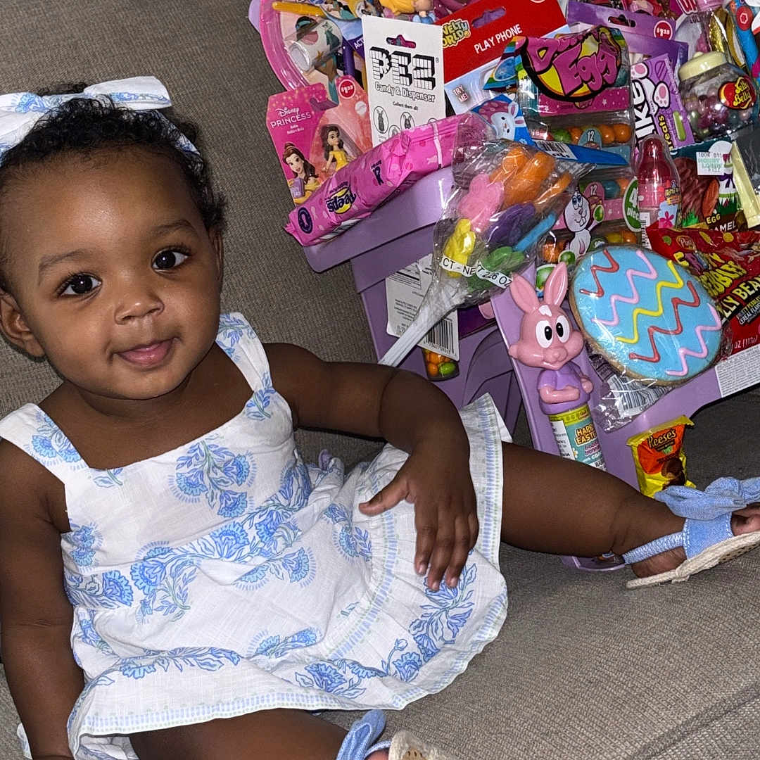 Ariana joined the competition — help win amazing prizes! bow, candy, child, colorful, couch, cute, dress, easter, footwear, happy, indoor, person, plush, portrait, seat, smile, snack, toddler, toy, young_child