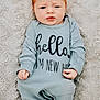 baby, infant, red_hair, onesie, text_on_clothing, blanket, lying_down, cute, newborn, person, skin, feet, hands, portrait, child, soft_texture, cozy, expression, casual_clothing, indoor