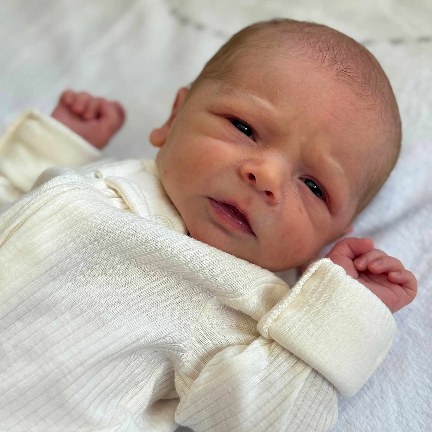 Cooper joined the competition — help win amazing prizes! baby, blanket, closeup, cozy, cute, expression, face, fist, head, human, indoor, infant, lying_down, newborn, newborn_clothes, portrait, skin, small_hands, soft_texture, white_clothing