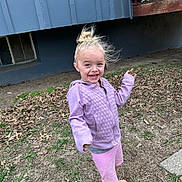 Laeklyn is registered to the contest to win money with this photo: child, smiling, barefoot, hoodie, shorts, outdoor, grass, dry_leaves, building, window, deck, wooden_railing, blonde_hair, messy_bun, happy, person, young, casual_clothing, nature, playful