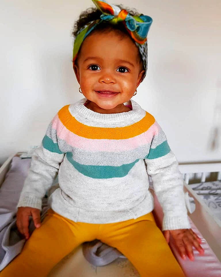 Aisha is registered to the contest to win money with this photo: baby, baby_products, baby_toddler_clothing, child, hair_accessory, head, headband, headgear, joy, person, play, sitting, skin, sleeve, smile, toddler, yellow