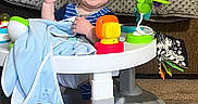 Daniel joined the competition — help win amazing prizes! baby, blanket, blue_clothing, cap, carpet, child, cute, drool, floor, furniture, happy, indoor, infant, person, playful, seated, smiling, toy, walker, waving