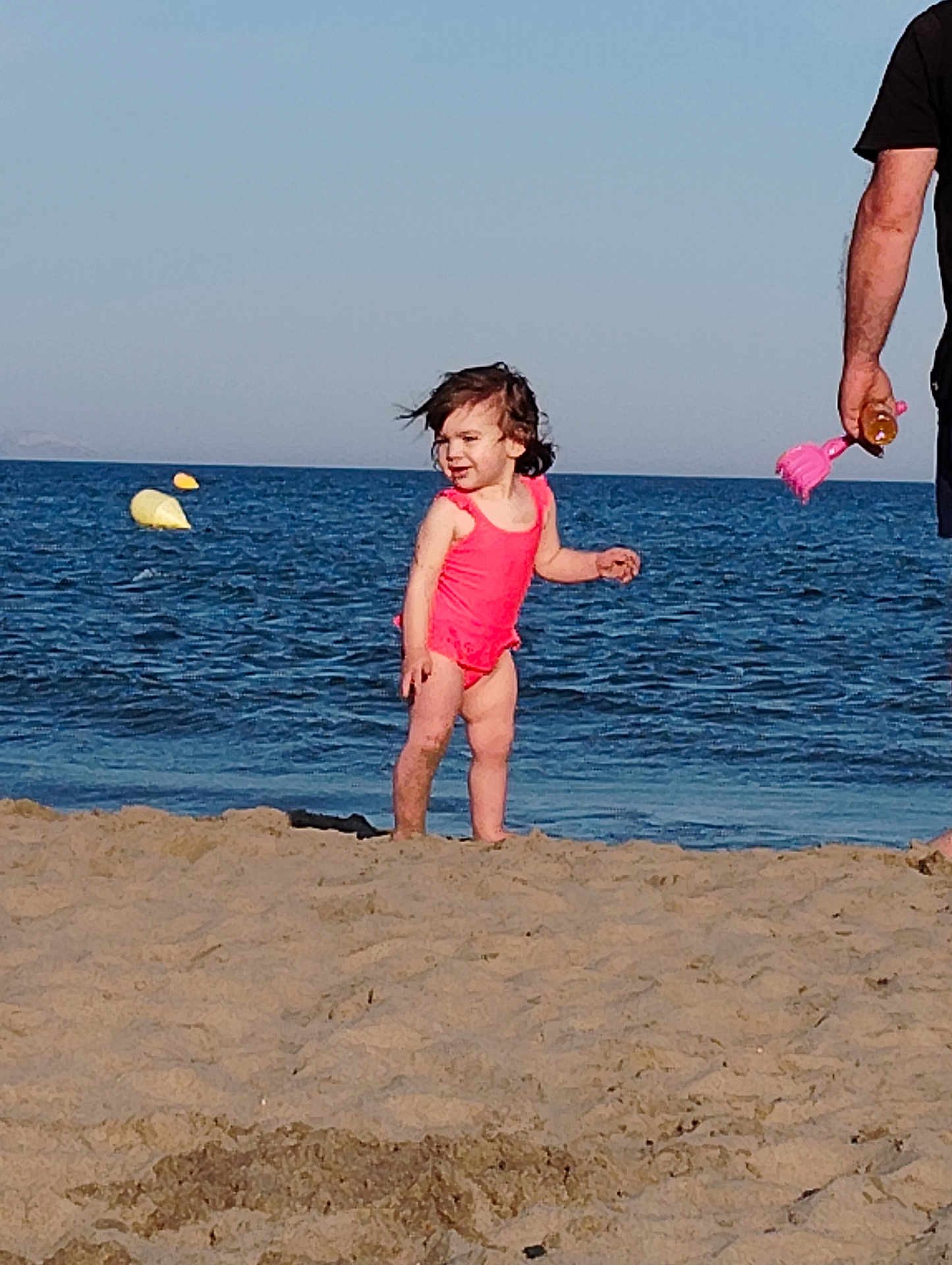June participe au concours pour gagner de l'argent avec cette photo : child, toddler, beach, sand, water, ocean, swimsuit, pink, sunny, daytime, person, adult, toy, sand_toy, outdoor, sky, waves, happy, hair, summer