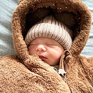 Diana participe au concours pour gagner de l'argent avec cette photo : baby, sleeping, hat, hood, jacket, brown, cozy, warm, infant, cute, face, child, soft, knit, zipper, closed_eyes, fur, clothing, portrait, indoors