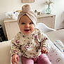 baby, child, cozy, cushion, cute, floral_sweater, flowers, furniture, happy, home_decor, indoor, infant, person, pink_pants, portrait, sitting, smiling, table, turban, vase