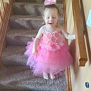 Emalee joined the competition — help win amazing prizes! barefoot, carpeted_stairs, child, cute, fun, girl, hair_bow, happy, holding_railing, home_interior, indoor, person, pink_dress, playful, small_child, smiling, staircase, tulle_skirt, wooden_railing, young_child