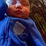 Gracie is registered to the contest to win money with this photo: baby, sleeping, blue_clothing, face, infant, child, person, camo_pants, lap, resting, peaceful, indoors, portrait, newborn, soft_light, cozy, closeup, cute, human, sleep