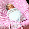 baby, bedding, blanket, cabinet, carpet, cozy, face, head, hearts_pattern, infant, newborn, nursery, peaceful, pink_blanket, plush, portrait, sign, sleeping, soft_texture, swaddled