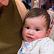 Victoire participe au concours pour gagner de l'argent avec cette photo : adult, baby, background_people, bib, blurred_background, candid, child, closeup, face, family, hand, holding, indoor, knitted_sweater, looking_down, love, person, smiling, table, warm_lighting