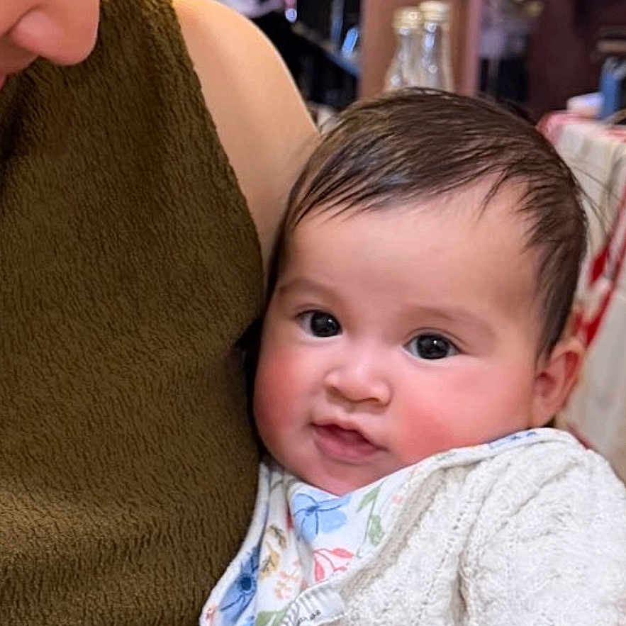 Victoire participe au concours pour gagner de l'argent avec cette photo : adult, baby, background_people, bib, blurred_background, candid, child, closeup, face, family, hand, holding, indoor, knitted_sweater, looking_down, love, person, smiling, table, warm_lighting