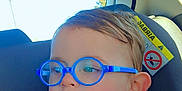 Maélän participe au concours pour gagner de l'argent avec cette photo : child, toddler, glasses, blue_glasses, eyewear, car_seat, car_interior, car_backseat, window, rear_window, seat_headrest, patterned_jacket, hoodie, heart_doodle, rosy_cheeks, ear, portrait, closeup, sunlight, safety_label