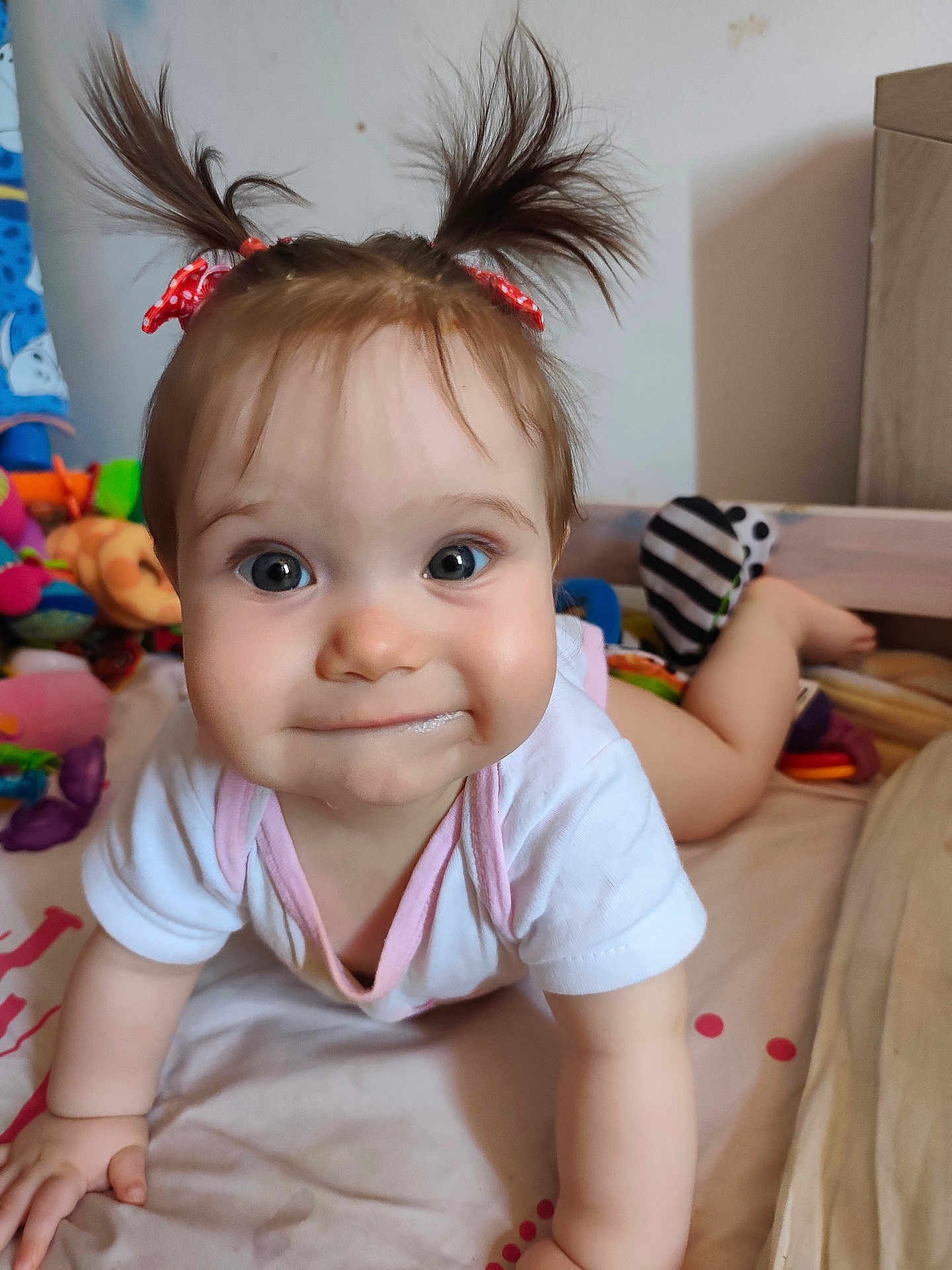Azurhya participe au concours pour gagner de l'argent avec cette photo : baby, child, pigtails, red_bows, crawling, bed, toys, curious, expression, indoor, clothing, white_shirt, pink_trim, face, hands, feet, cute, playful, smile, person