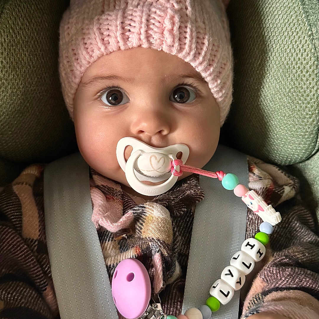 Lyli participe au concours pour gagner de l'argent avec cette photo : accessories, baby, beanie, bodypart, bonnet, cap, car, clothing, couch, face, finger, furniture, hand, hat, head, jewelry, necklace, person, photography, portrait