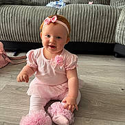 Joanie-May is registered to the contest to win money with this photo: baby, girl, pink_clothing, headband, smile, sitting, floor, couch, indoor, child, tulle, sock, cute, happy, infant, person, toddler, home, decor, portrait
