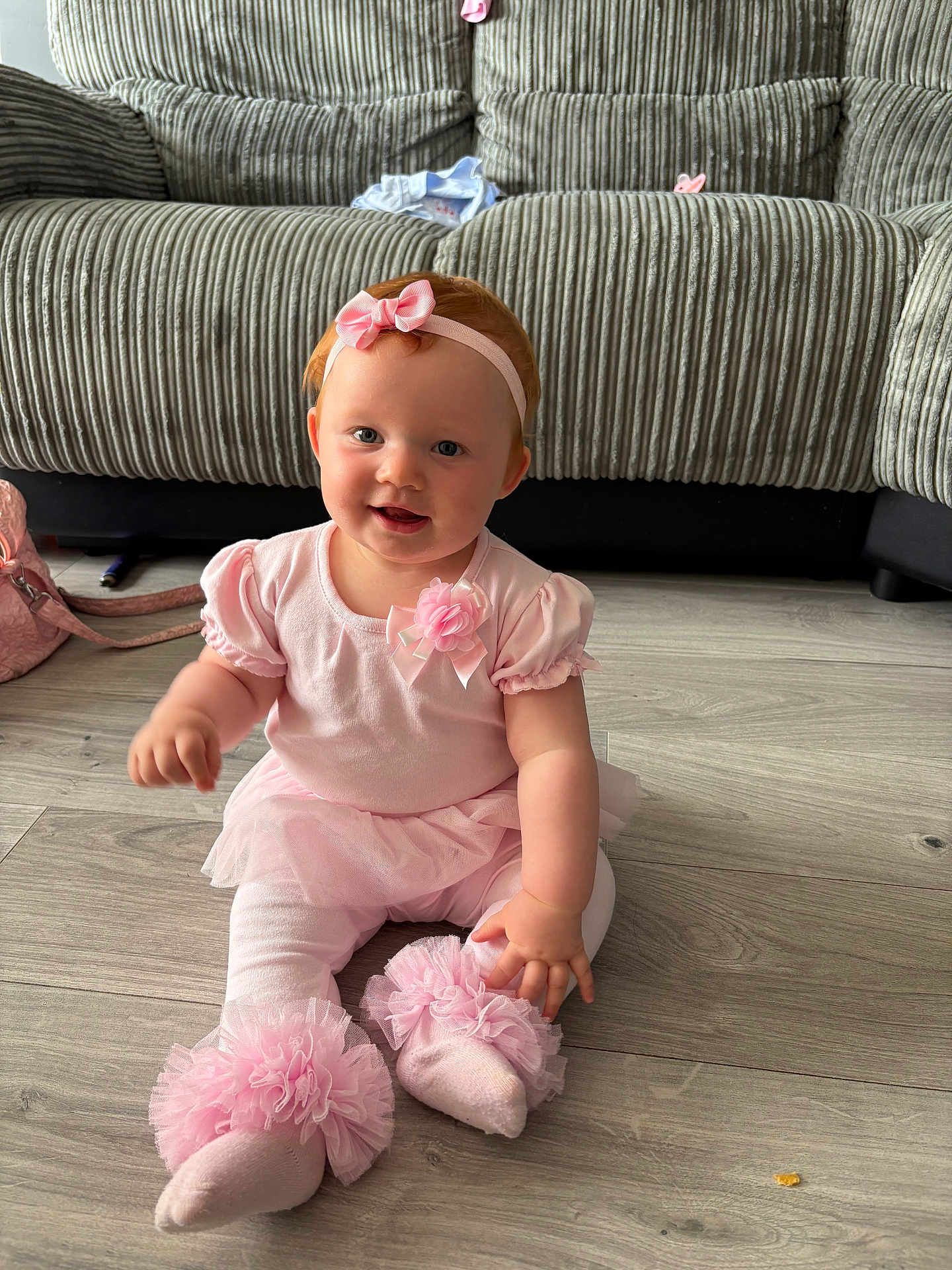 Joanie-May is registered to the contest to win money with this photo: baby, girl, pink_clothing, headband, smile, sitting, floor, couch, indoor, child, tulle, sock, cute, happy, infant, person, toddler, home, decor, portrait
