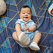 Chadric Ashton is registered to the contest to win money with this photo: baby, infant, child, smiling, sitting, portrait, indoors, bed, bedspread, blue, geometric_pattern, clothing, light_blue_outfit, shoes, white_shoes, toy, pillow, happy, playful, photography