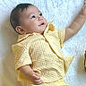 Chadric Ashton is registered to the contest to win money with this photo: adorable, baby, blanket, child, close_up, dark_hair, eyes, face, hand, indoor, infant, looking_up, lying_down, open_mouth, portrait, quilt, raised_arm, soft_lighting, textured_outfit, yellow_clothing