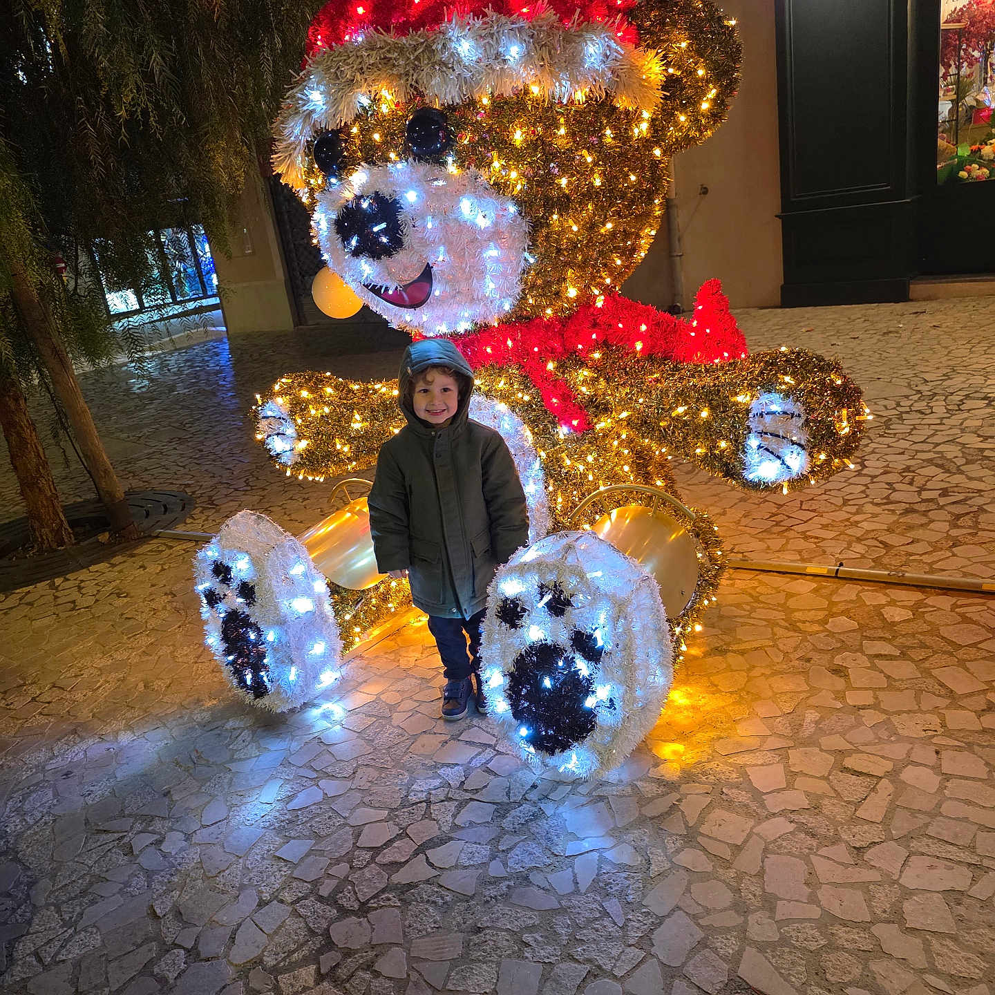 Sandro a rejoint le concours — aidez-le/la à gagner de superbes lots ! child, christmas, cobblestone, decoration, face, festive, happy, holiday, hoodie, illumination, lights, night, outdoor, person, scarf, seasonal, smile, teddy_bear, toy, winter
