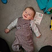 Tony participe au concours pour gagner de l'argent avec cette photo : baby, card, carpet, child, clothing, cute, face, floor, happy, indoor, infant, lying_down, overalls, person, playful, smiling, socks, toddler, toy, young_child