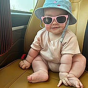 Daisy is registered to the contest to win money with this photo: accessory, baby, car_seat, child, chubby, clothing, cute, fashion, foot, hand, hat, indoor, person, portrait, seat, seatbelt, skin, smiling, sunglasses, window