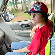 Mikey is registered to the contest to win money with this photo: accessories, baseballcap, belt, cap, car, clothing, face, hat, head, helmet, pants, person, photography, plant, portrait, sitting, t_shirt, transportation, vegetation, vehicle