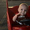 toddler, child, shopping_cart, red, parking_lot, night, smile, face, person, steering_wheel, playful, clothing, outdoor, urban, cute, baby, expression, toy, vehicle, seat