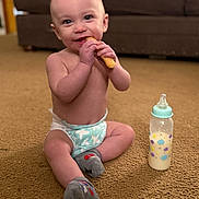 Leighton joined the competition — help win amazing prizes! baby, infant, diaper, sitting, carpet, milk_bottle, snack, smiling, happy, indoors, child, cute, sock, food, milk, person, young_child, floor, bottle, home