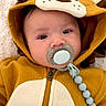 baby, infant, child, lion_costume, animal_onesie, hood, pacifier, pacifier_clip, lying_down, portrait, face, eyes, cozy, blanket, white_blanket, indoor, close_up, cute, brown_clothing, nursery