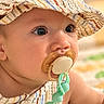 baby, child, infant, portrait, face, eyes, pacifier, pacifier_clip, sun_hat, hat, striped_clothing, overalls, bib, sitting, indoor, close_up, soft_lighting, textile, blanket, cute