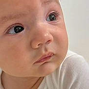 Dylan is registered to the contest to win money with this photo: baby, infant, child, portrait, close_up, face, eyes, looking_at_camera, curious, serious_expression, fair_skin, brown_hair, white_clothing, blanket, indoor, soft_lighting, photography, head, shoulders, adorable