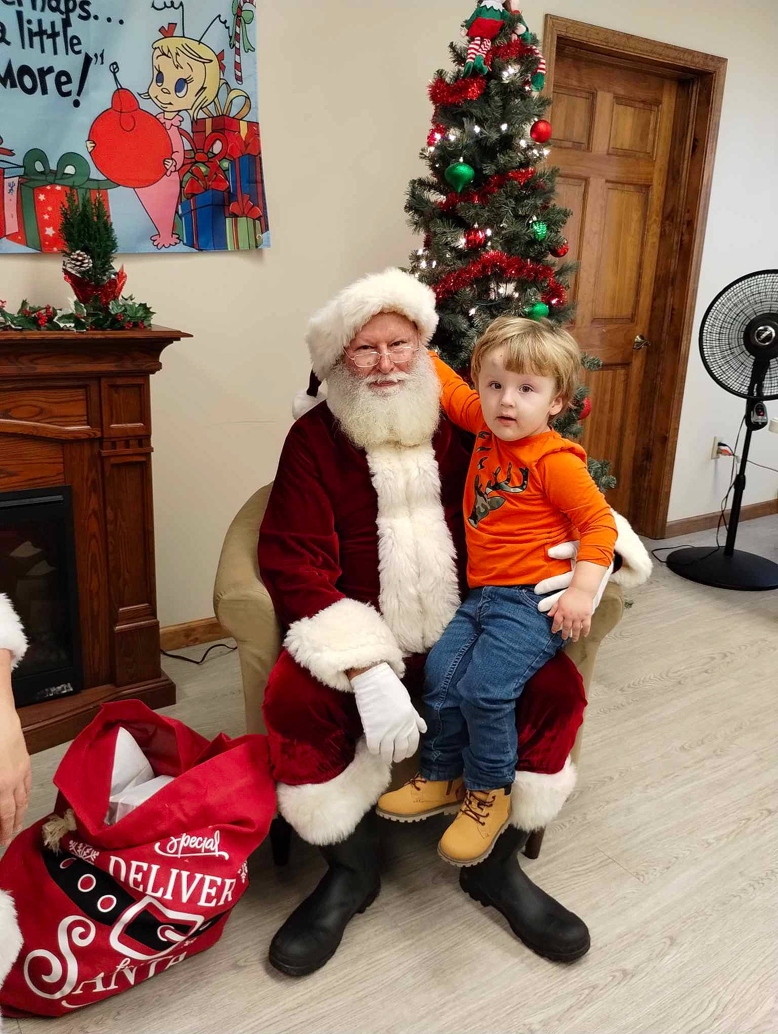 Dereck joined the competition — help win amazing prizes! boot, christmas, christmas_decoration, christmas_eve, christmas_ornament, christmas_tree, event, fictional_character, happy, hat, headwear, holiday, holiday_ornament, lap, mechanical_fan, person, plant, red, santa_claus, smile