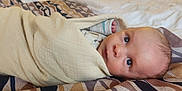 Oakley is registered to the contest to win money with this photo: baby, bedspread, blanket, cozy, curious, eyes, fabric, face, head, indoors, infant, lying_down, newborn, patterned, person, portrait, skin, sleepwear, soft, wrapped
