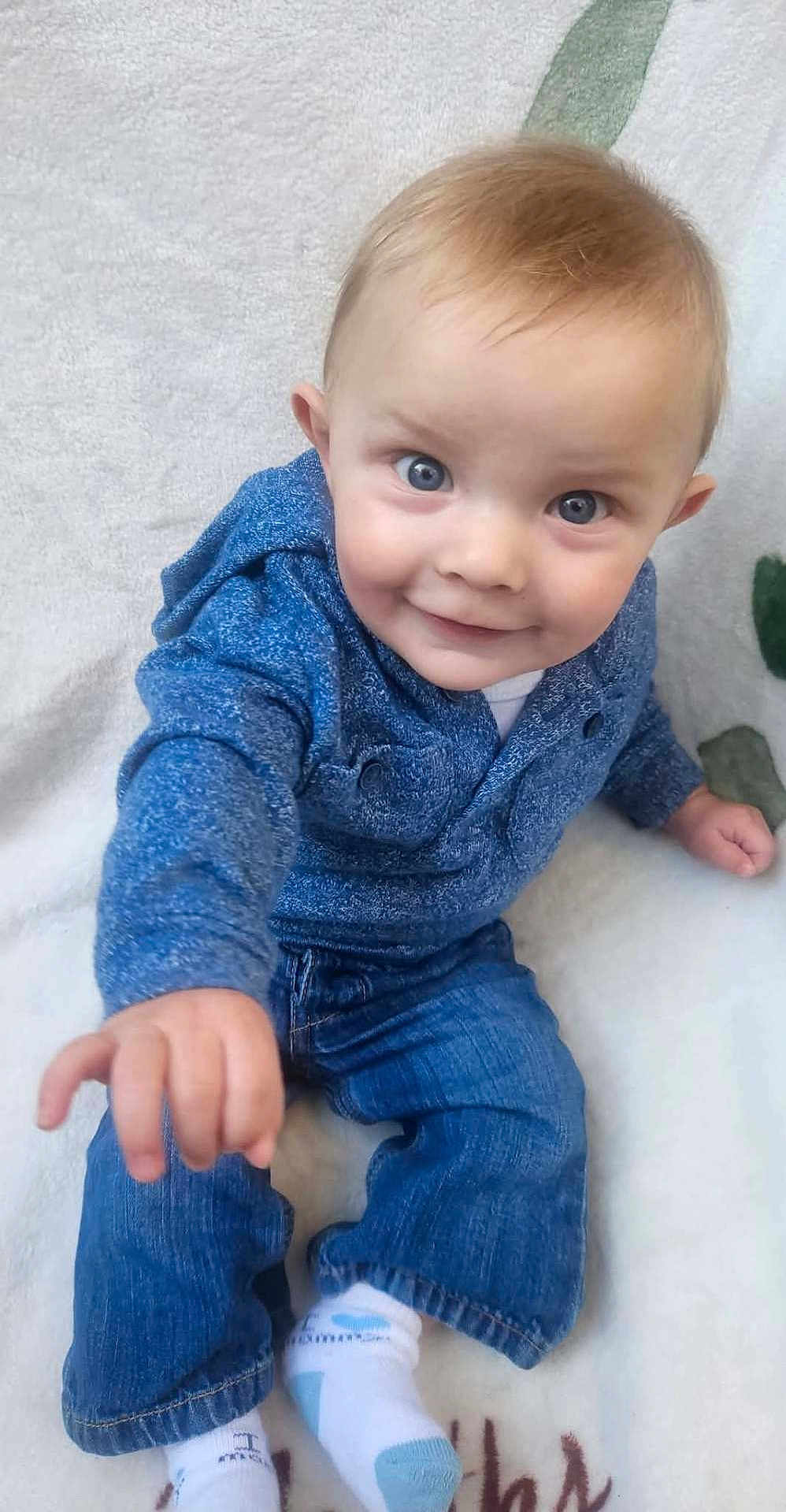 Oakley joined the competition — help win amazing prizes! toddler, child, baby, blue_eyes, hoodie, jeans, socks, smiling, happy, indoor, blanket, curious, cute, portrait, person, clothing, baby_clothes, skin, face, hand