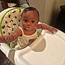Naiari is registered to the contest to win money with this photo: baby, high_chair, food, messy, indoor, child, cute, curious, face, clothing, arm, seat, furniture, person, table, skin, expression, room, happy, young