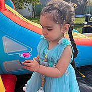 Nina a rejoint le concours — aidez-le/la à gagner de superbes lots ! child, girl, blue_dress, toy, outdoor, playground, inflatable, beaded_hair, curious, daylight, grass, backyard, summer, young_child, portrait, side_view, cute, play, person, casual
