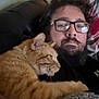 Calcifer is registered to the contest to win money with this photo: man, cat, glasses, beard, orange_tabby, couch, blanket, indoor, relaxing, snuggling, pet, fur, portrait, home, casual, comfort, resting, close_up, animal, leisure