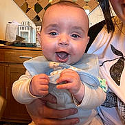 Noah participe au concours pour gagner de l'argent avec cette photo : baby, child, infant, smiling, happy, person, bib, clothing, hand, face, indoor, kitchen, cabinet, mirror, adult, holding, table, furniture, portrait, cute