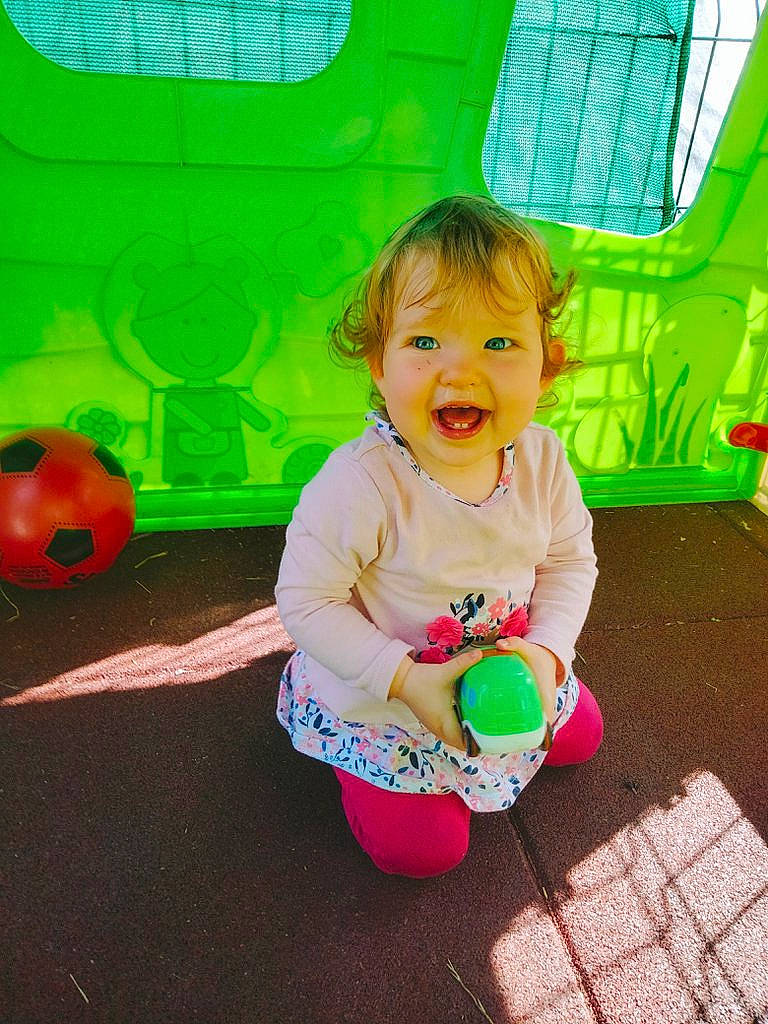 Victorine participe au concours pour gagner de l'argent avec cette photo : baby, baby_toddler_clothing, child, fun, grass, green, happy, leisure, magenta, mammal, people_in_nature, person, pink, play, recreation, sitting, smile, t_shirt, toddler, window