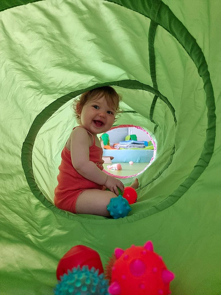 Victorine participe au concours pour gagner de l'argent avec cette photo : baby_toddler_clothing, comfort, eye, facial_expression, fun, grass, hand, happy, head, human_body, leaf, leisure, organ, people_in_nature, person, pink, product, recreation, smile, textile